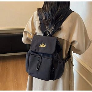 Detail showing the large capacity black backpack with yellow embroidery on the cover flap