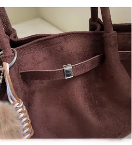 Vue détaillée du sac cabas en daim marron avec boucles argentées et pompon en peluche