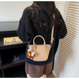 Litchi texture apricot mini tote bag with plush charm shown in a cozy interior setting