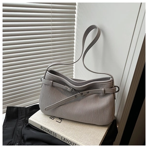 Macro view of gray pleated corduroy texture and decorative strap on shoulder bag