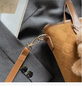 Detail of brown suede bucket bag featuring embossed texture and golden metal hardware