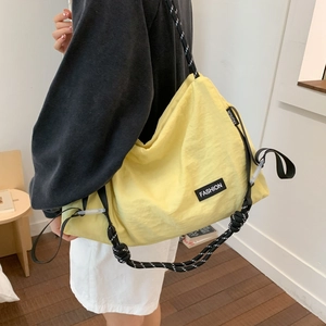 Detail of light yellow nylon tote bag with fashion tag and woven shoulder strap