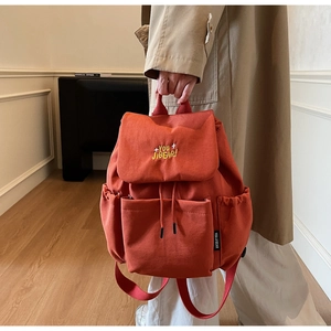 Detail of red-brown canvas backpack with YOU JIBEAR embroidery and flap closure