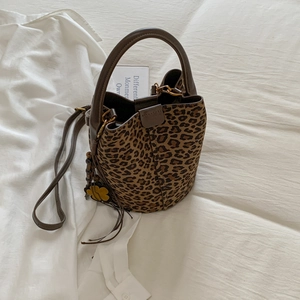 Detailed top view of leopard print bucket bag with brown handles and floral charm