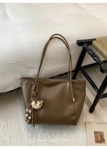 Grand sac fourre-tout rétro avec breloque ours et perles dans un décor intérieur douillet