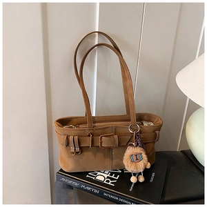 Brown suede tote bag detail featuring a vintage belt buckle and plush lion charm