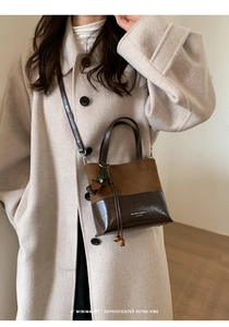 Detail view of retro bucket bag with contrasting textures and tassel accessory on model