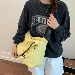 Detailed close-up of bright yellow canvas shoulder bag featuring trendy drawstrings and text tag