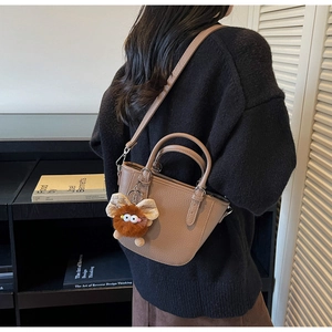 Brown litchi grain leather mini bucket bag with a cute plush monster charm detail
