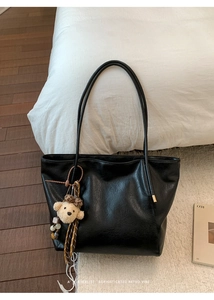 Détail du grand sac cabas noir en similicuir avec un pendentif d'ours en peluche brun