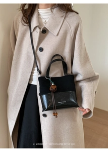 Detail of vintage black bucket bag featuring suede contrast and floral tassel charm