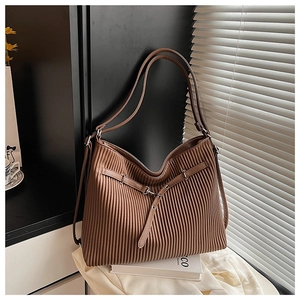 Detailed view of brown pleated tote bag with decorative buckle in natural light setting