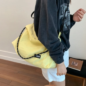 Detail of bright yellow tote bag featuring black and white woven rope shoulder straps