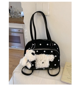 Detail of black polka dot handbag with plush dog patch and matching bag charm