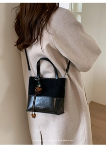 Detail of black patchwork bucket bag with wooden bead tassel and minimalist logo