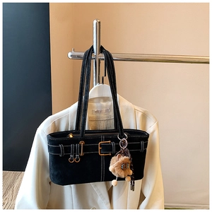 Close-up of black suede bucket bag with contrast stitching and fuzzy monster charm