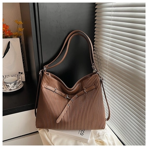 Detail of a brown tote bag featuring pleated texture and adjustable buckle strap