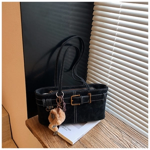 Detail of black suede underarm bag with contrast stitching and plush lion charm