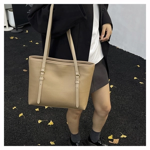 Detail of khaki pebbled leather tote bag featuring gold ring hardware and adjustable straps