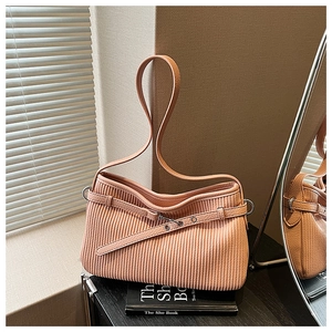 Close-up of peach pink pleated handbag with textured fabric and metal buckle detail