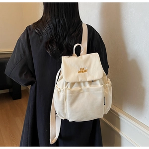 Detail of off-white canvas backpack featuring YOU JIBEAR embroidery and side pocket