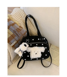 Detail of black polka dot handbag with plush puppy patch and matching charm on sofa