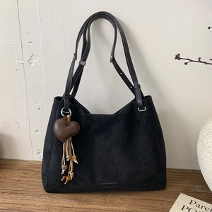 Black matte tote bag detail with brown leather heart charm and ethnic wood bead accents