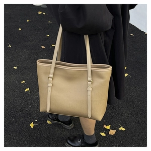 Detail shot of khaki leather tote bag with gold hardware on autumn gingko background