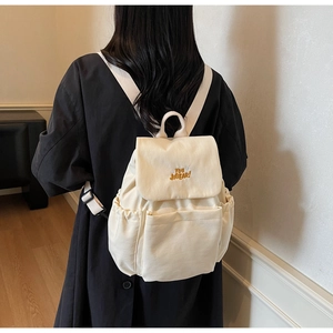 Close-up of off-white canvas backpack featuring YOU JIBEAR embroidery and front pockets