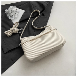 Close-up of pleated white hobo bag with detachable straps on a grey blazer background