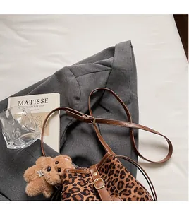 Detail of leopard print bucket bag with adjustable leather strap and plush bear charm