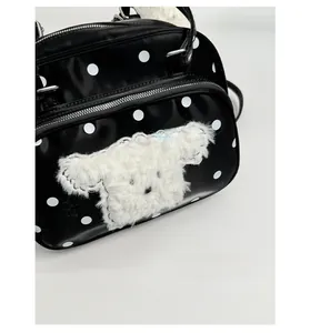 Close-up of black polka dot handbag featuring a 3D plush puppy patch with blue ribbon