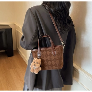 Brown suede bucket bag with quilted patterns and a cute puppy charm shown on a model