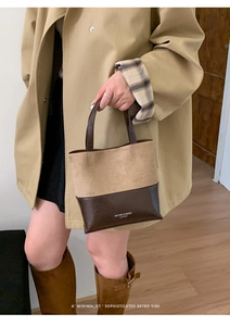 Detail of two-tone bucket bag with brand logo shown with casual trench coat and boots