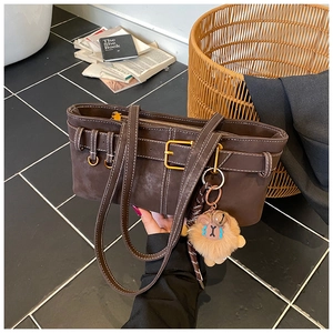 Detail of dark brown suede handbag with contrast stitching and plush lion charm