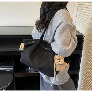 Detail der schwarzen Wildleder-Shopper mit Lederriemen und braunem Teddybär-Anhänger