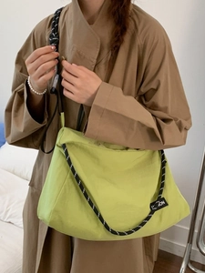 Neon green nylon crossbody bag with woven shoulder strap and fashion label shown on model