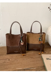 Close-up of vintage bucket bag featuring suede texture, leather trim and tassel charm