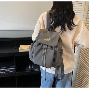 Detail of dark grey nylon backpack with embroidered yellow stars and drawstring closure