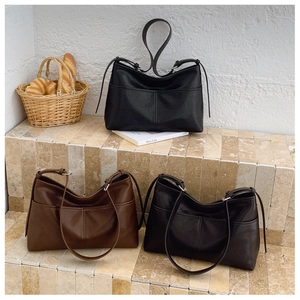 Detail view of large faux leather tote bags in brown and black on stone steps