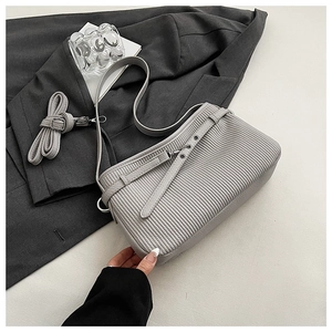 Detailed macro of grey bucket bag showing vertical ribbed texture and silver eyelet strap