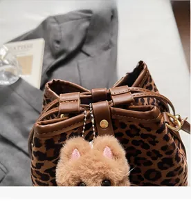 Detail view of leopard print plush bucket bag with drawstring closure and doll charm