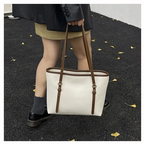 Street style view of large beige tote bag with brown trim and lychee texture