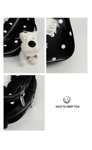 Detailed view of polka dot pattern, silver zipper, and white plush puppy charm on bag