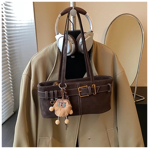 Detail view of dark brown suede bucket bag with gold buckle and fuzzy animal charm