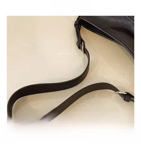 Detail view of smooth black leather tote bag with adjustable silver metal buckle