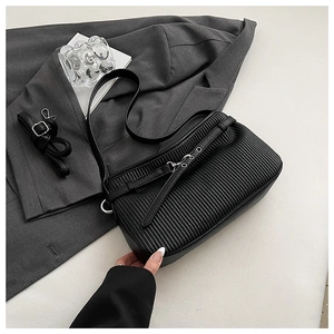 Detail of black pleated shoulder bag with silver hardware and adjustable strap