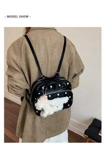 Polka dot backpack with plush dog charm shown on model for size and style reference