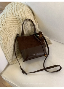 Detailed view of retro bucket bag with suede splicing and tassel charm on sofa
