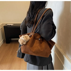 Braune Wildleder-Tote-Bag mit Kordelzug und Plüschhund-Anhänger, von Modell getragen